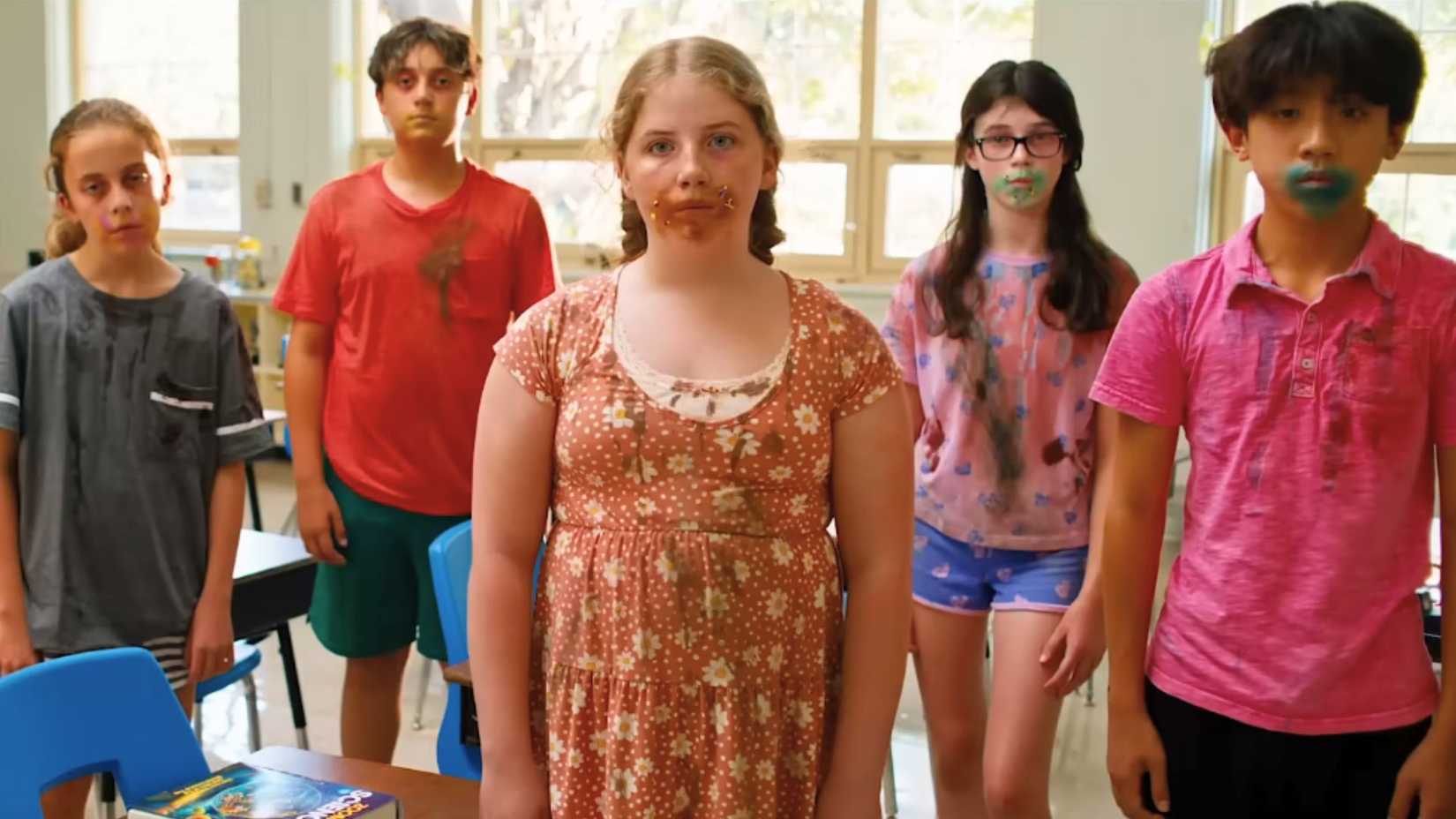 Dazed looking children stare creepily ahead with ice cream sprinkles around their mouth.