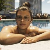 A woman sits in a pool with her martini.
