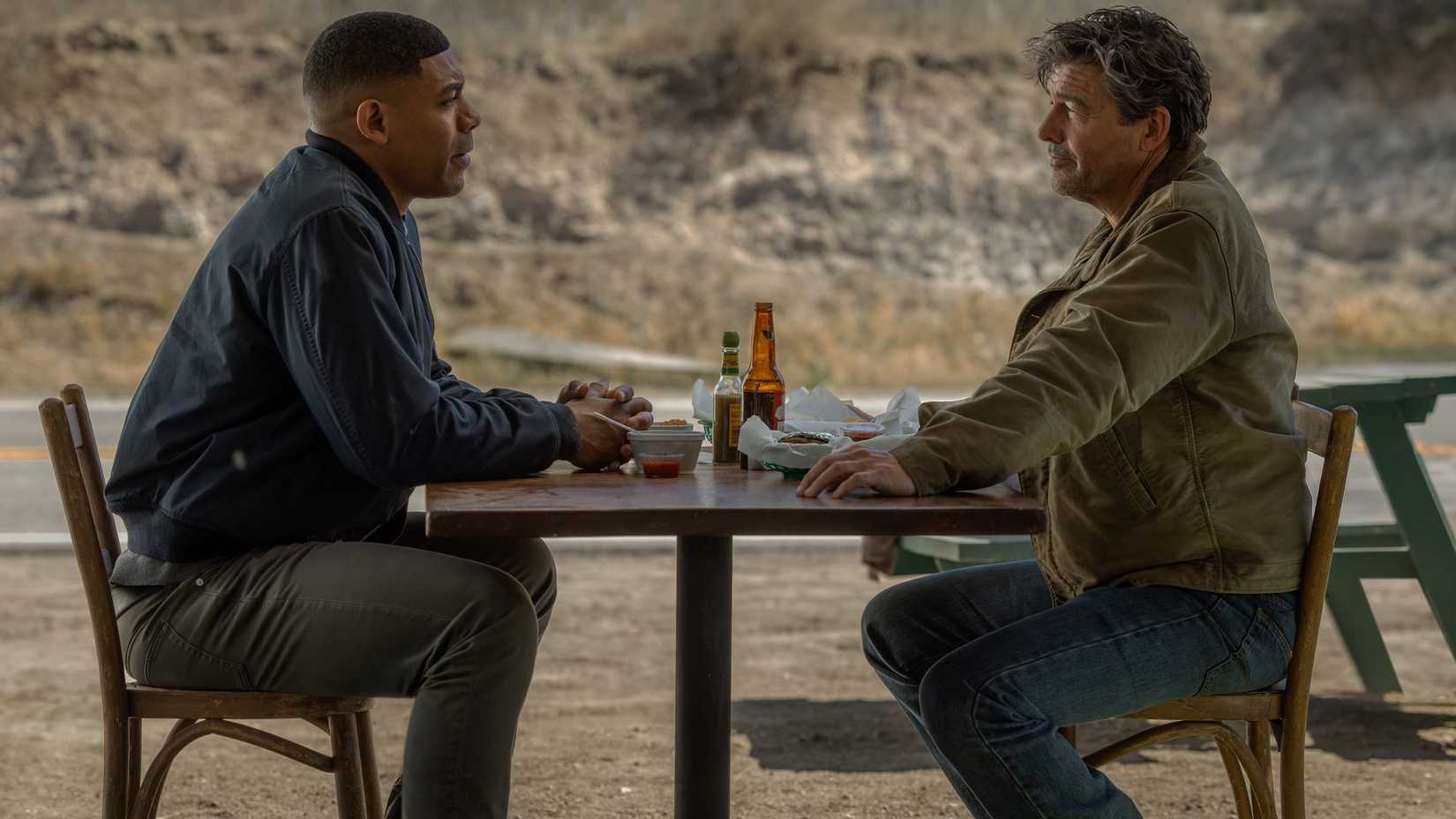 John Stewart (Aaron Pierre) and Hal Jordan (Kyle Chandler) sit at a picnic table eating in Lanterns