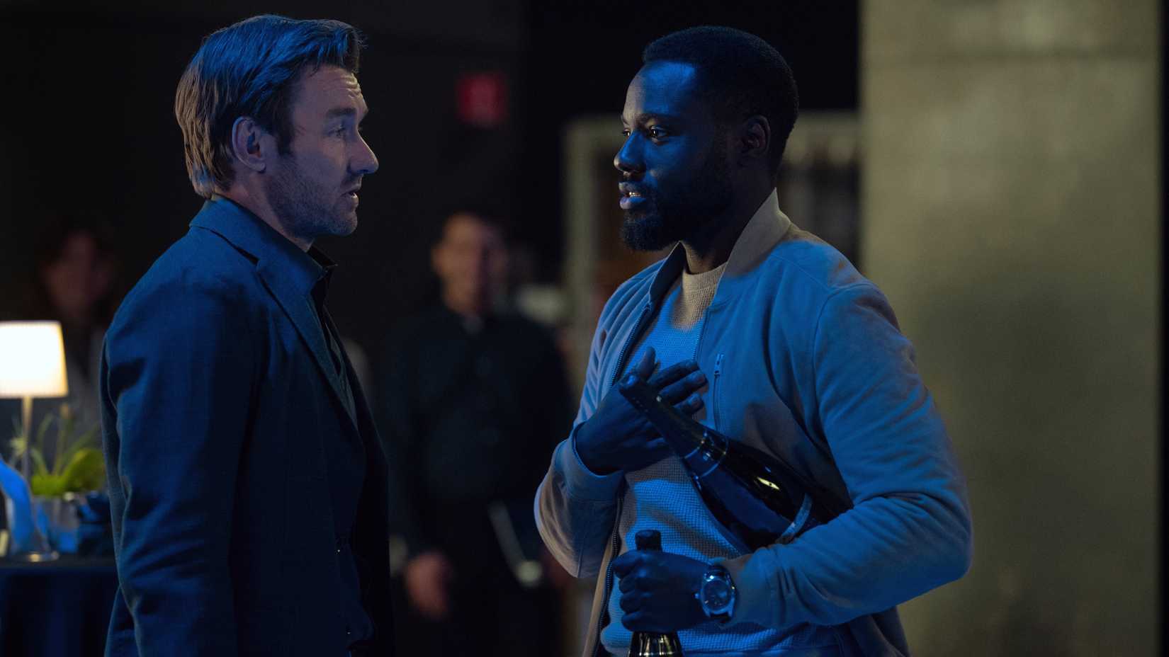 Jason Dessen (Joel Edgerton) talks to Leighton Vance (Dayo Okeniyi), who is carrying two bottles of champagne in Dark Matter season 2