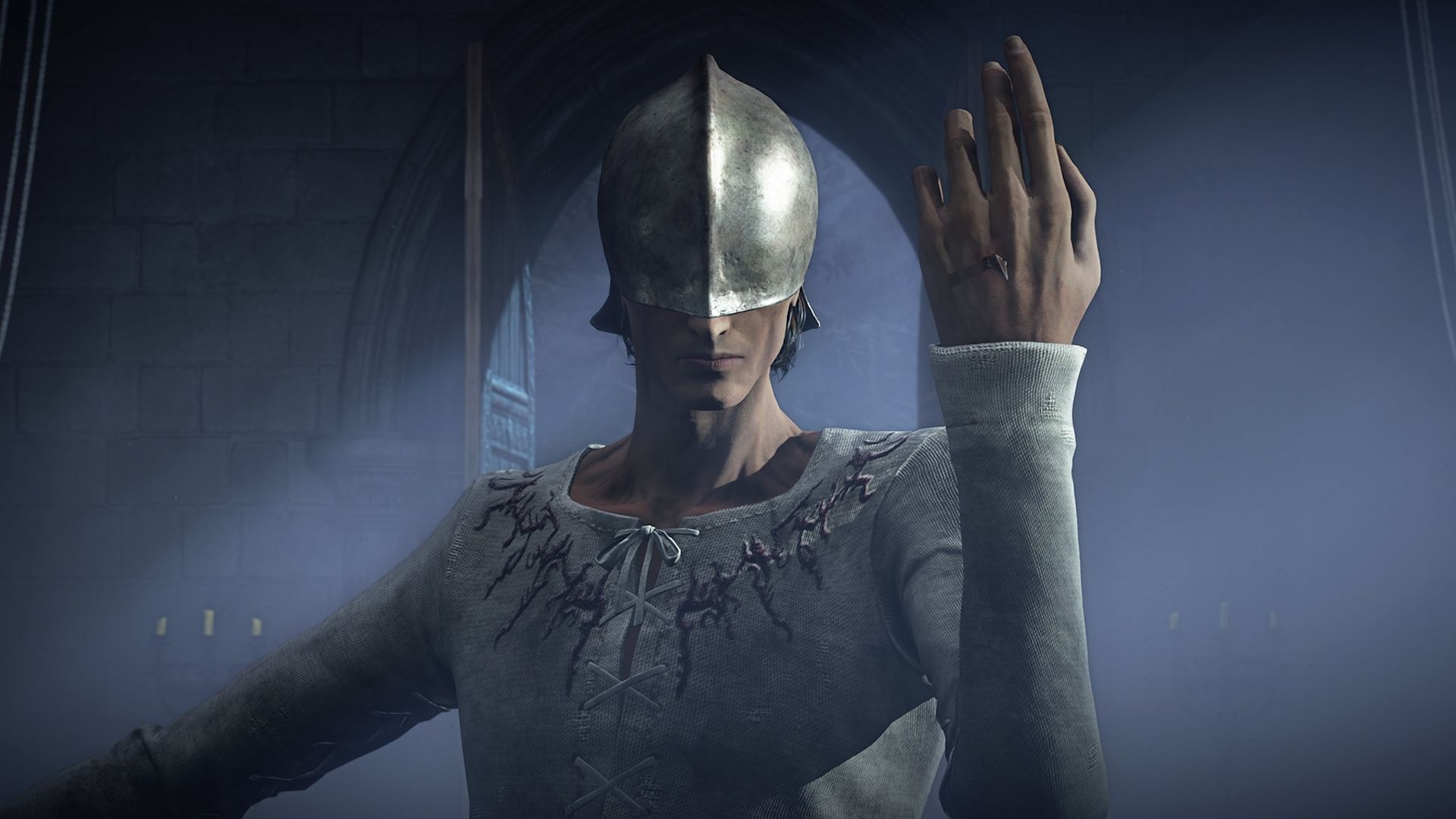 A man wearing a helmet over his eyes holds the back of his hand up to the viewer