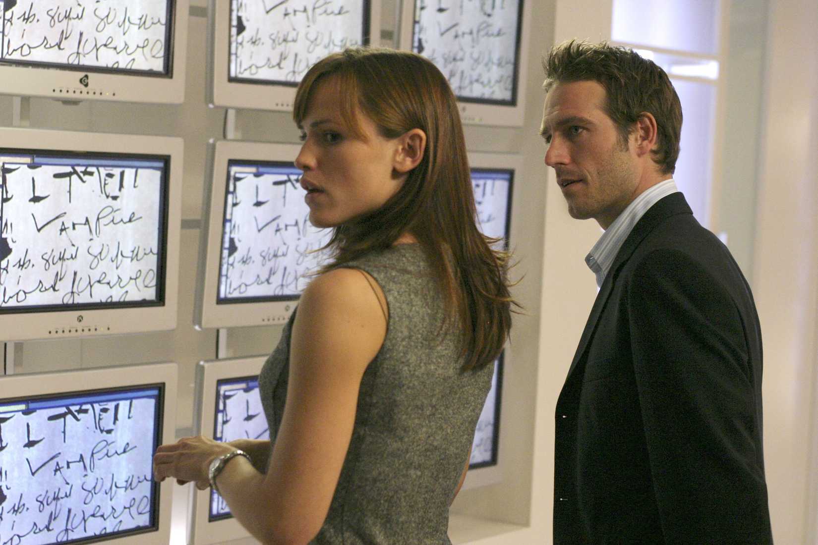 Jennifer Garner and Michael Vartan standing in front of screens in the TV show Alias