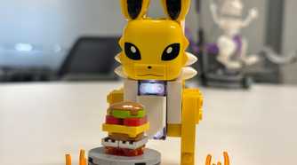 A Lego Jolteon stands in front of a toy burger.