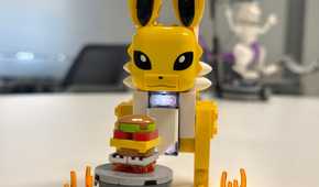 A Lego Jolteon stands in front of a toy burger.