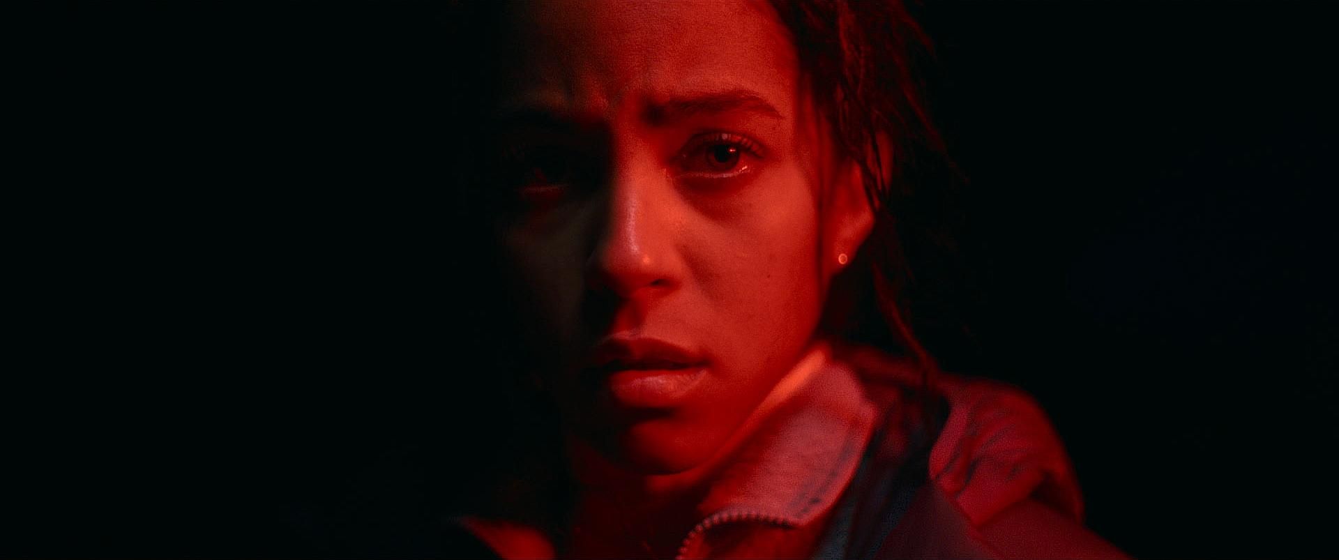 Lou Llobell covered in red light in the movie Passenger