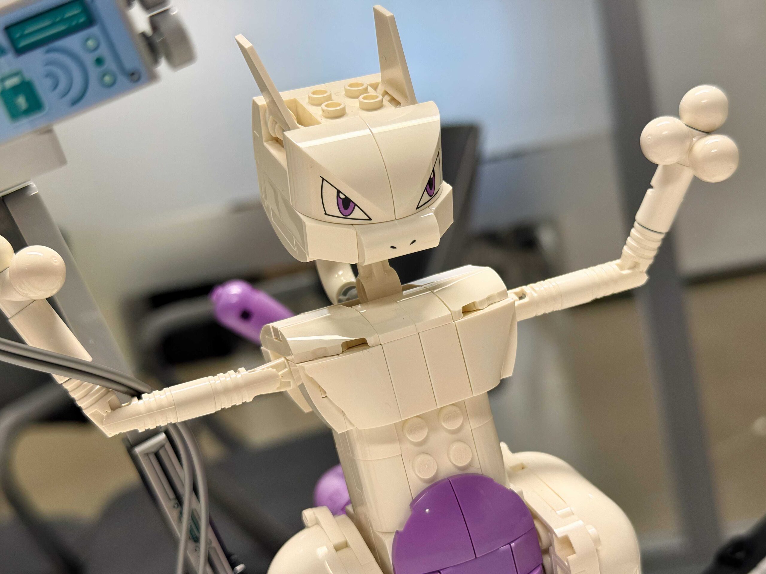 A Lego Mewtwo stands with its arms raised.