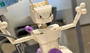 A Lego Mewtwo stands with its arms raised.