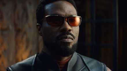 A close-up of Yahya Abdul-Mateen II as Wonder Man in Wonder Man, in a black leather super-suit, with red sunglasses