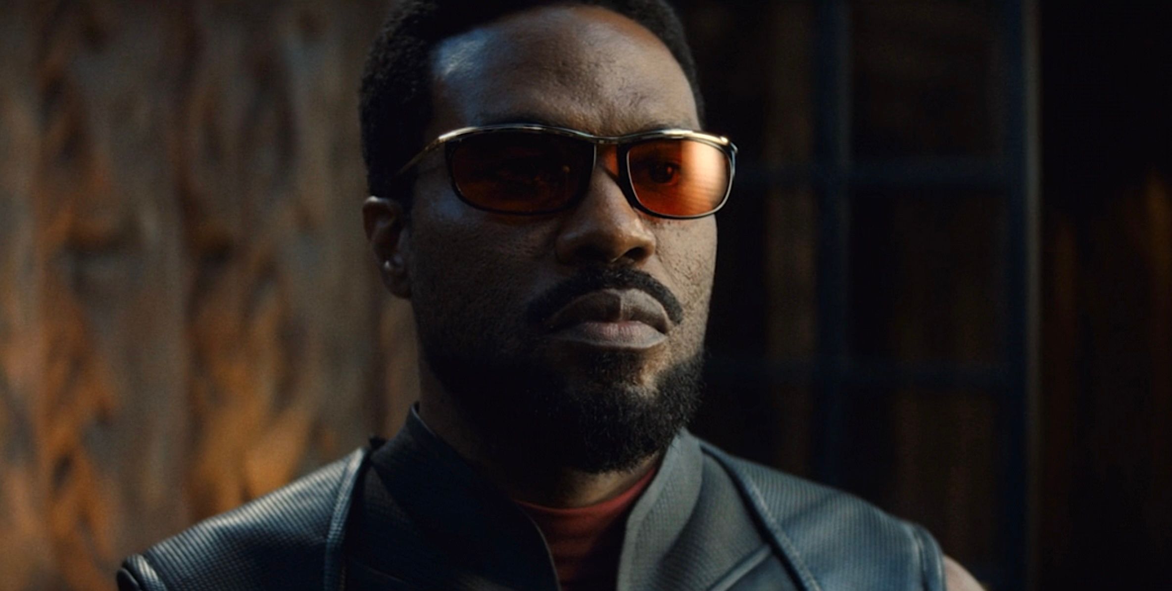 A close-up of Yahya Abdul-Mateen II as Wonder Man in Wonder Man, in a black leather super-suit, with red sunglasses
