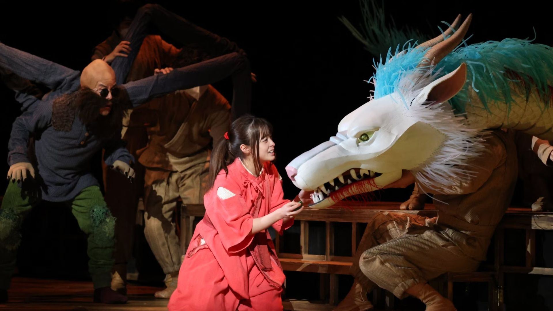 Scene from live action spirited away play featuring a dragon and the main character
