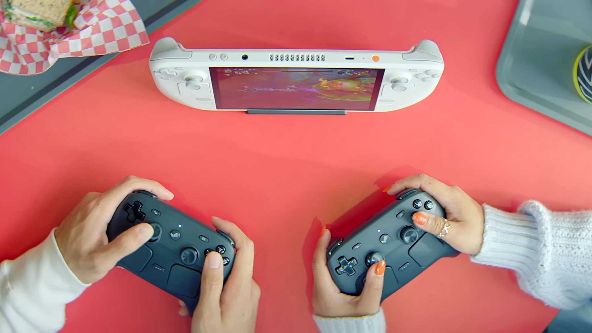 A still of two players using Steam Controllers to play on a handheld PC