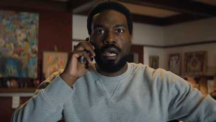 Yahya Abdul-Mateen II as Simon Williams in Wonder Man takes a call on his cell phone with his eyes and mouth wide open in shock