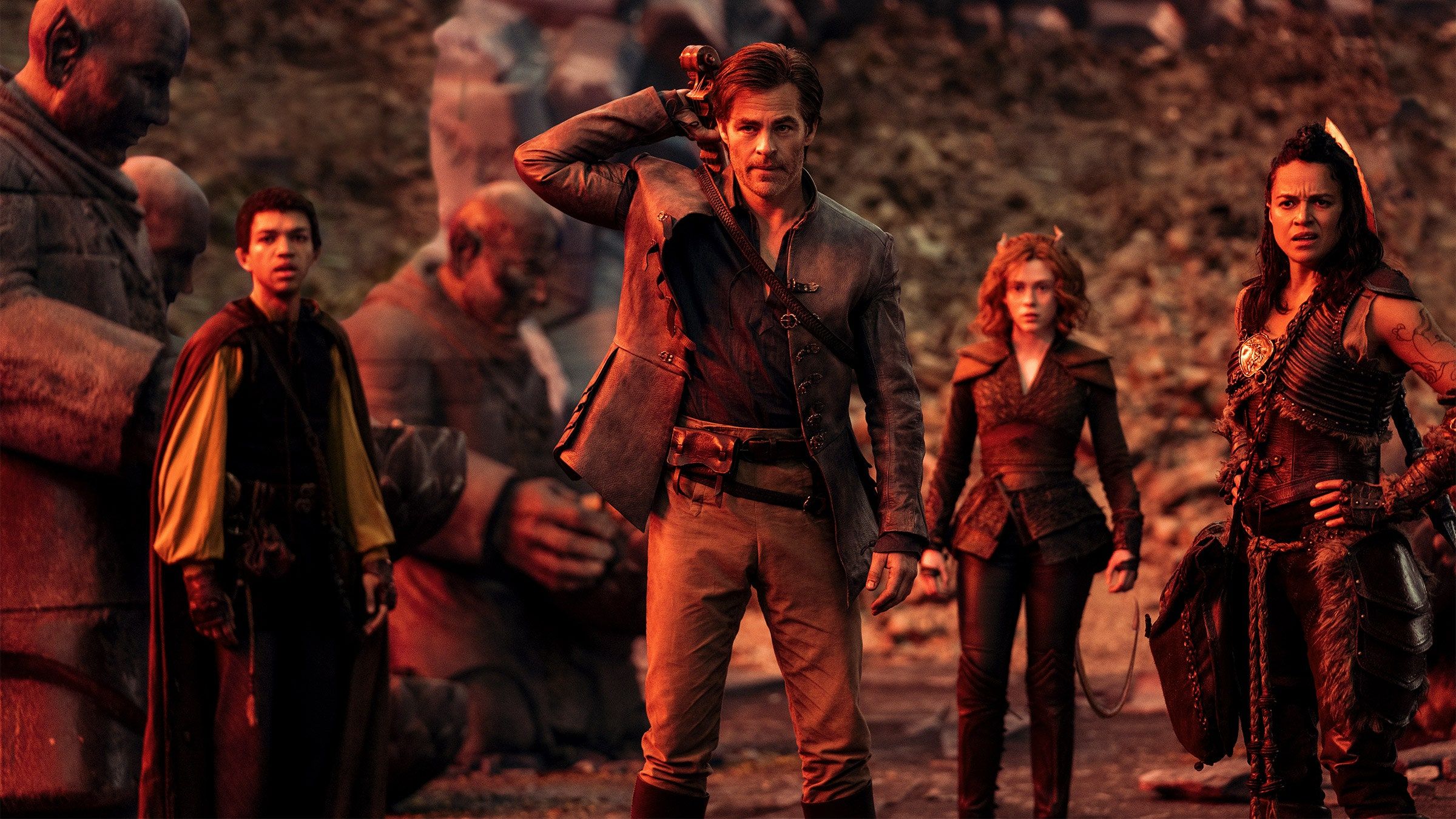 (L-R) The half-elf sorcerer Simon (Justice Smith), the human Bard Edgin (Chris Pine), the tiefling&nbsp;druid Doric (Sophia Lillis), and the Barbarian warrior Holga (Michelle Rodriguez) standing in a valley flanked by solemn looking statues in Dungeons & Dragons: Honor Among Thieves.