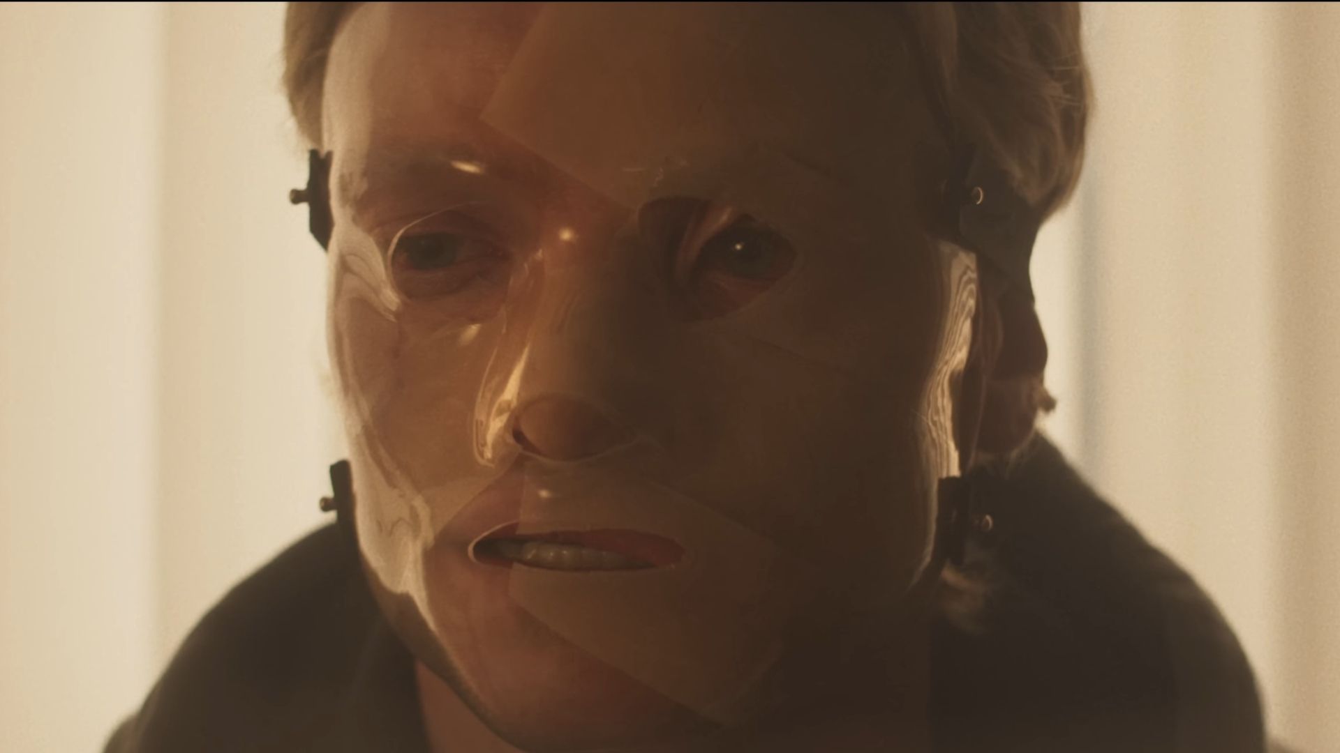 A man in a haunting, partially translucent mask.