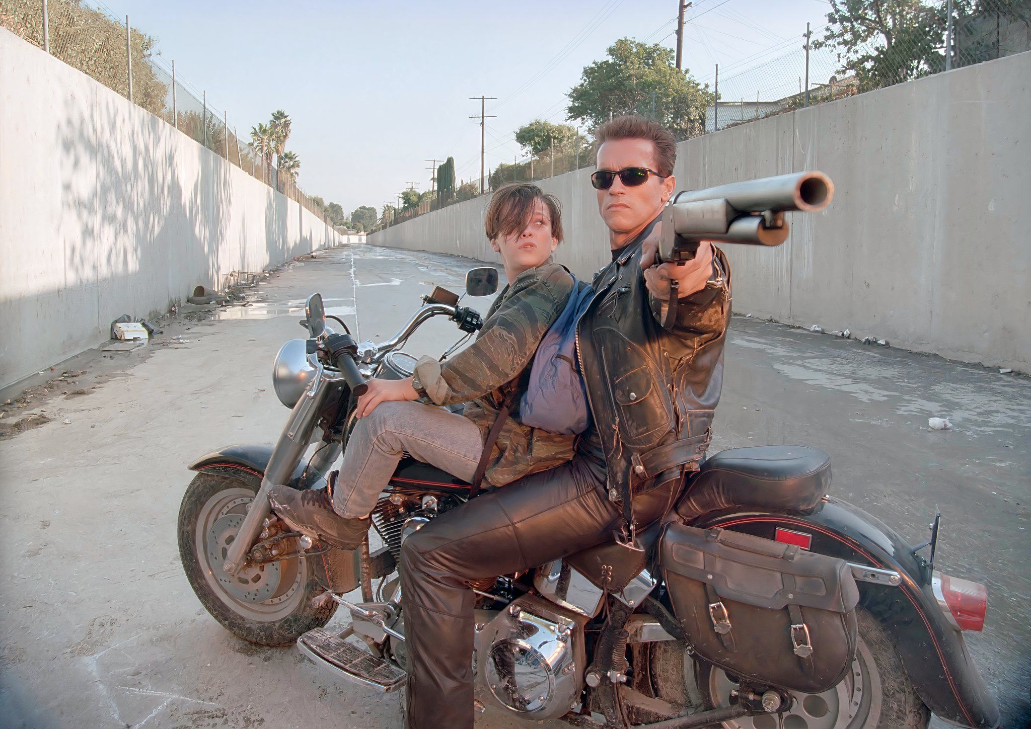 The Terminator points a gun as a young John watches in Terminator 2