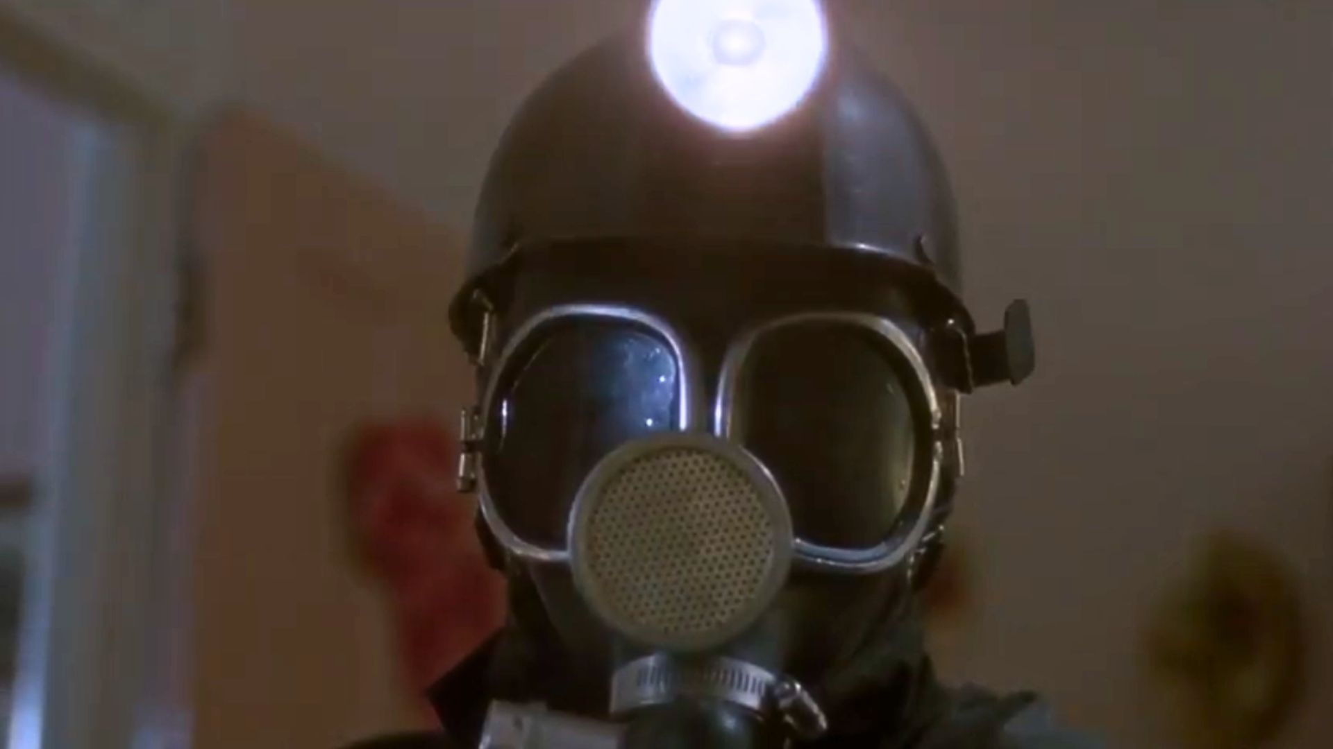 An image of a man decked out in black mining gear. He wears a black, domed helmet with a light on top.