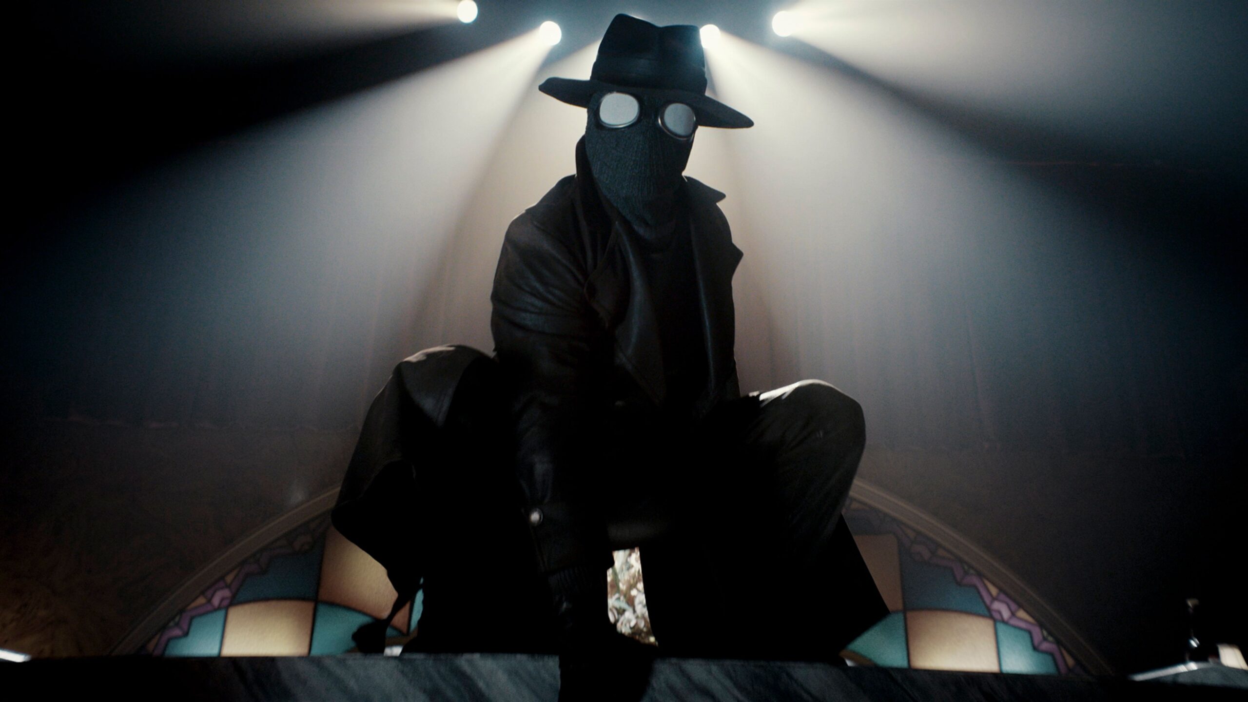 Spider-Noir (Nic Cage) wearing a black mask with white eyes and a fedora perches in front of stained glass in Spider-Noir