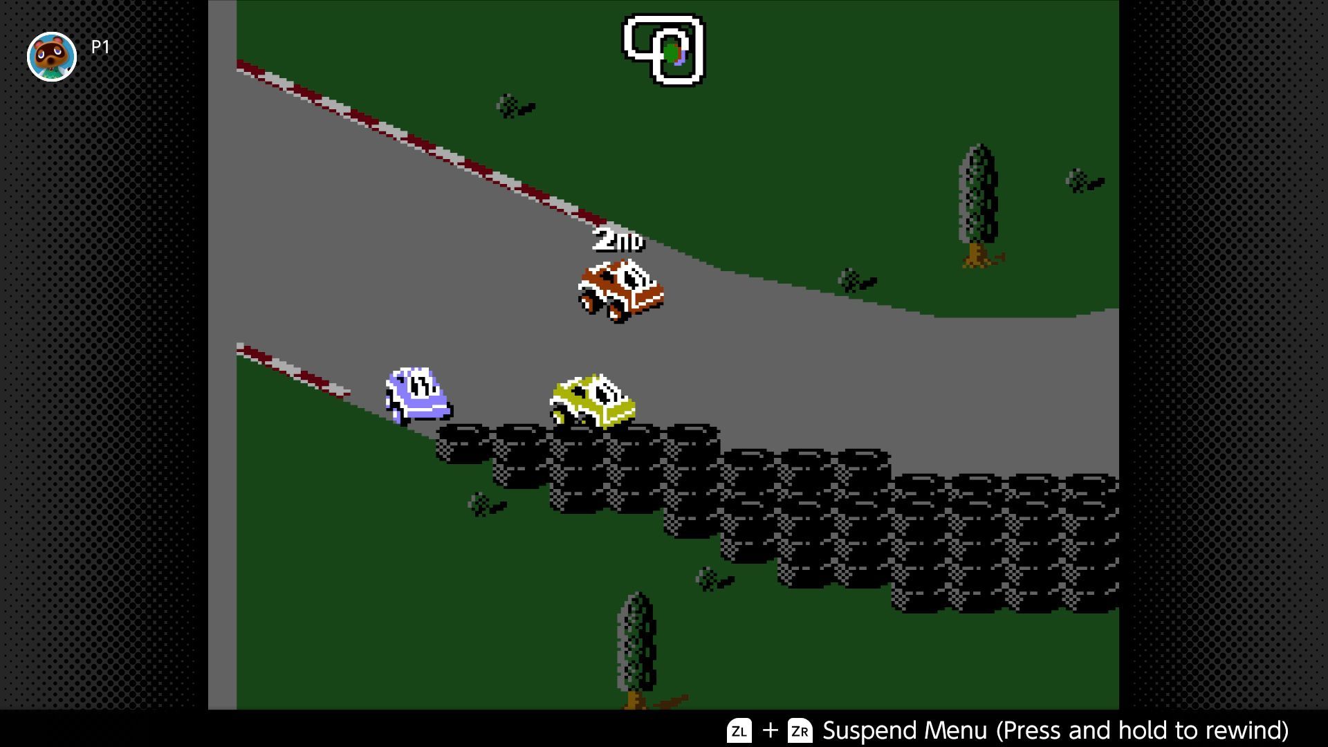 RC Pro-Am 2 screenshot - In the grasslands, vehicles round a bend with a barrier of stacked tires