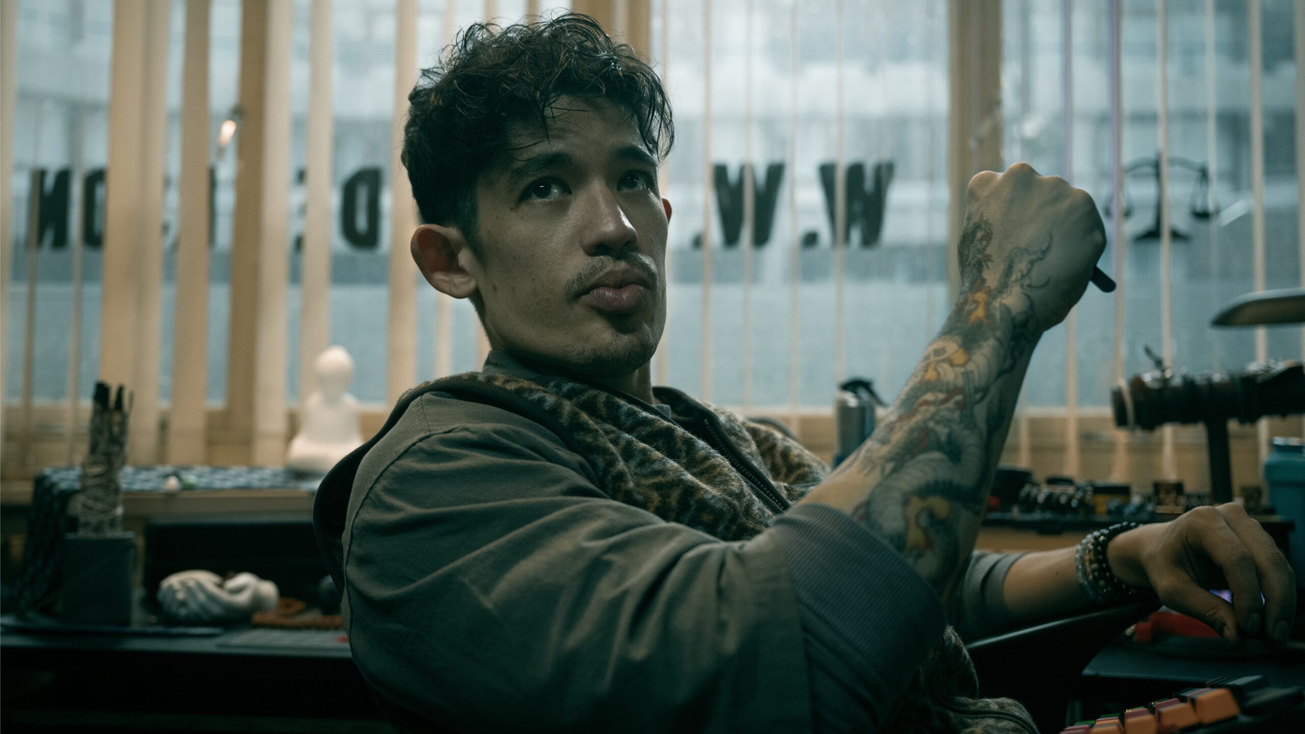 Roddy Ho (Christopher Chung) sits at his desk in Slow Horses season 6.