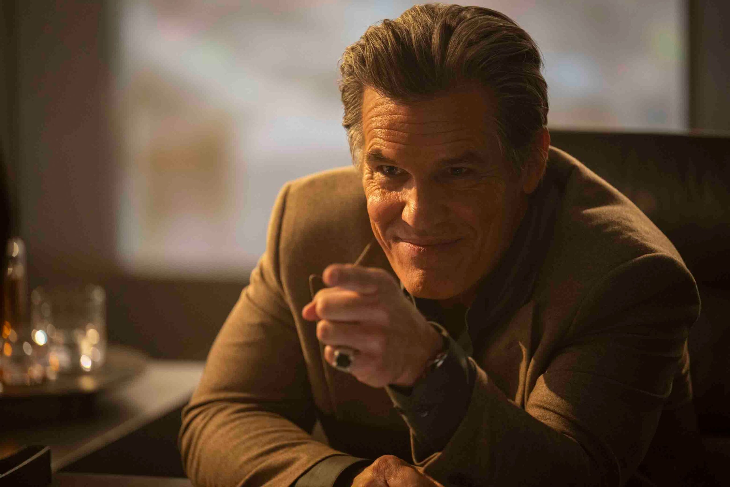 Killian (Josh Brolin) smirks and points across a desk in The Running Man 2025