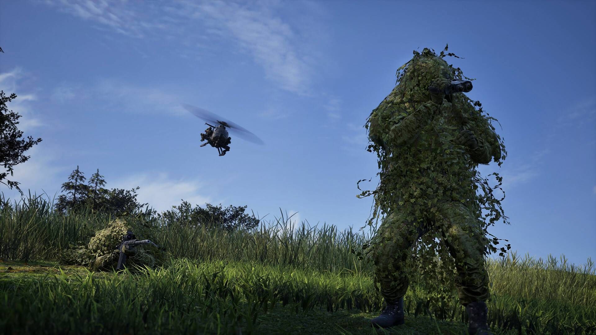 Two soldiers in ghillie suits in a field while a helicopter flies above them in Wardogs.