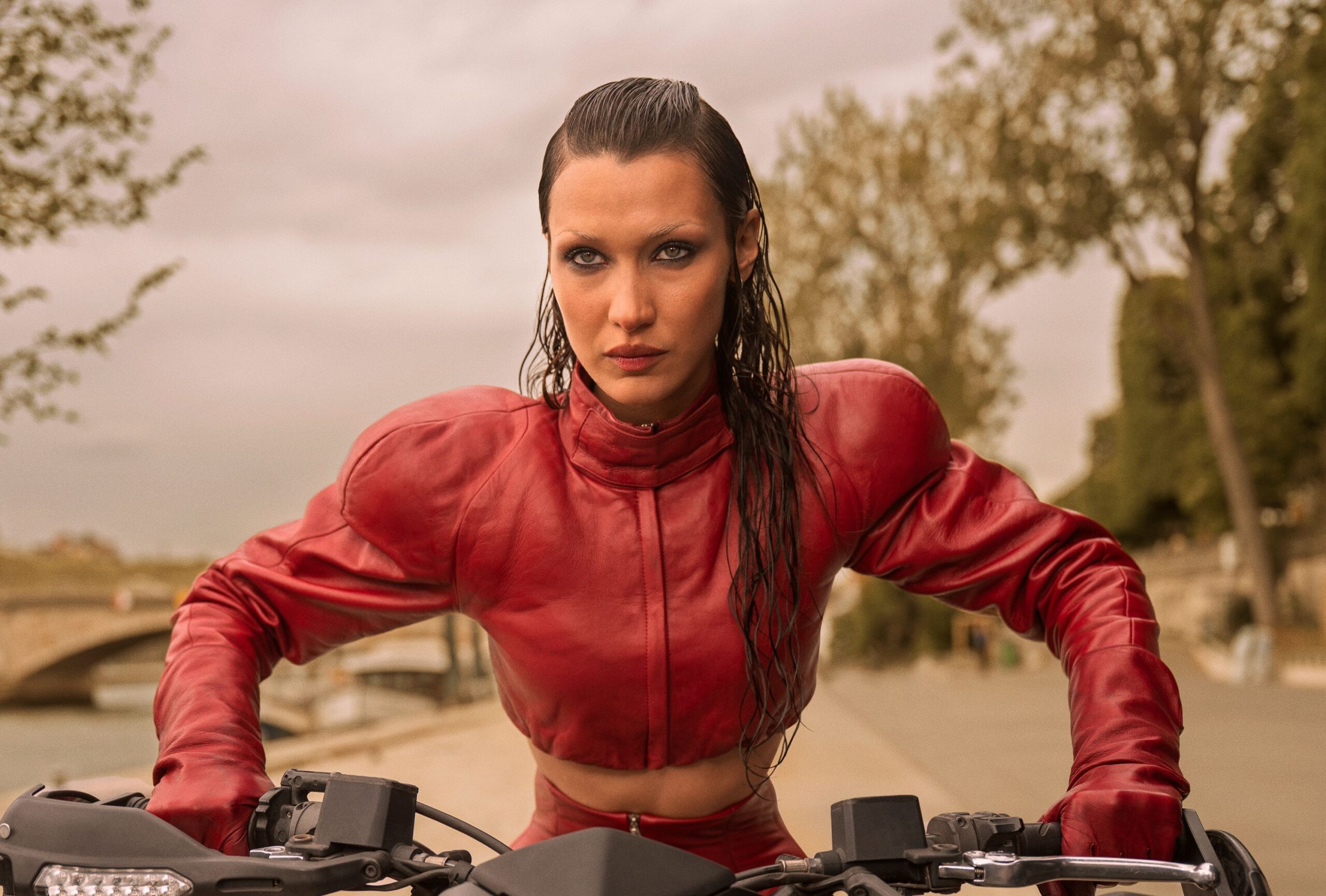 An image from The Beauty. It shows a seriously sweaty model decked out in red leather, riding a motorbike. 