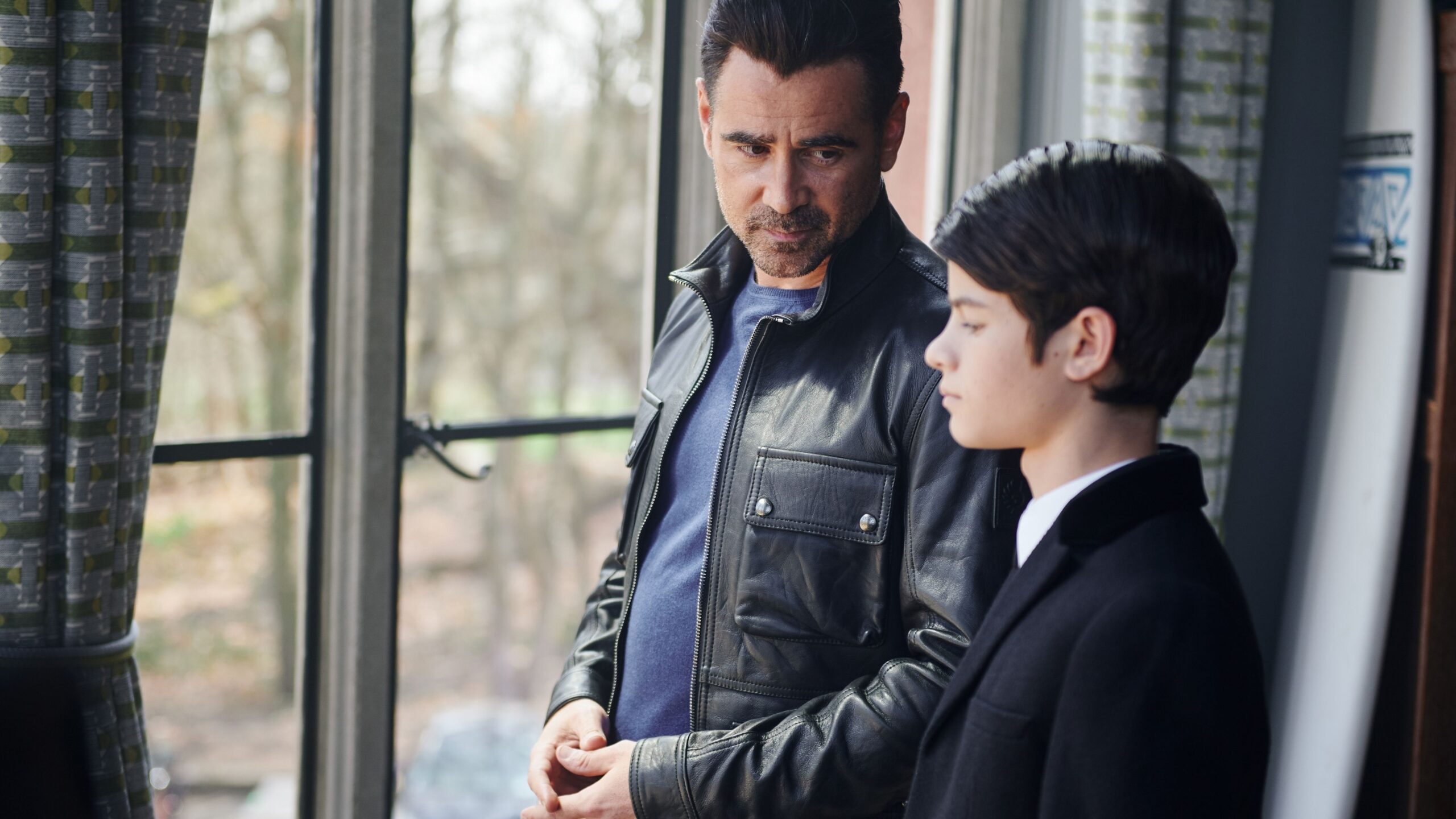 a father and son stand by a window