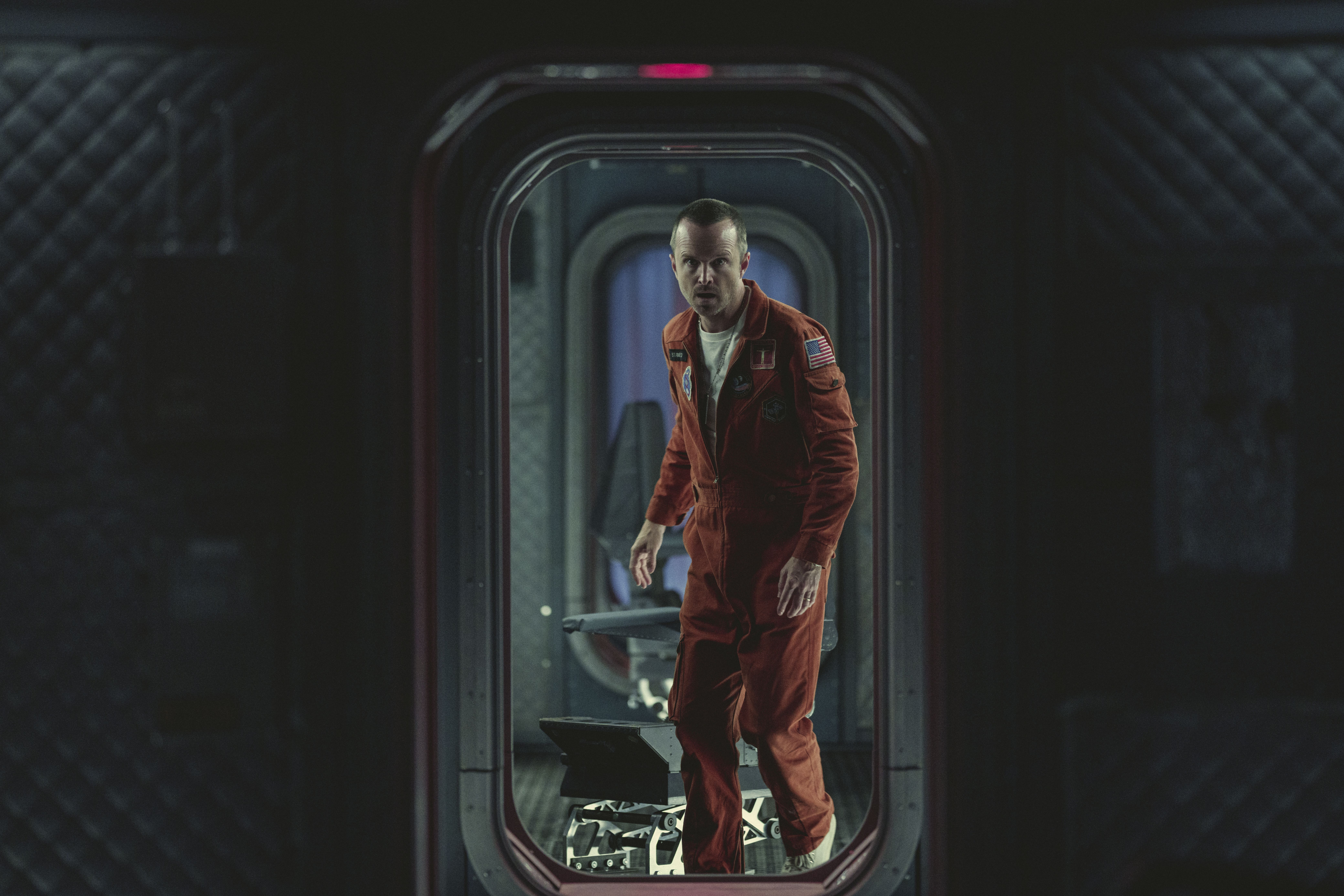 Aaron Paul in a spacesuit looking through a doorway with shock in a still from Black Mirror season 6