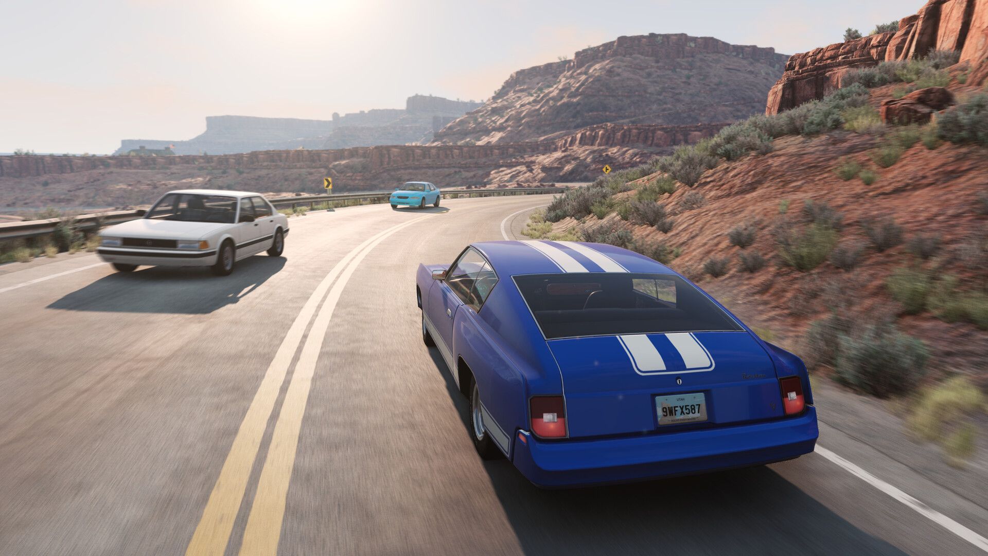A muscle car powers along a road among canyons