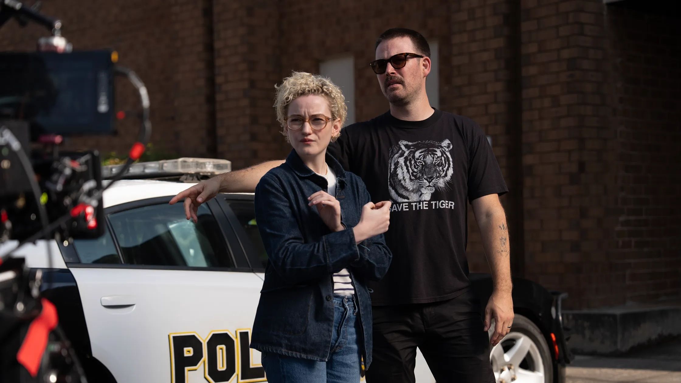 Zach Cregger directs Julia Garner in front of a police car on the set of Weapons