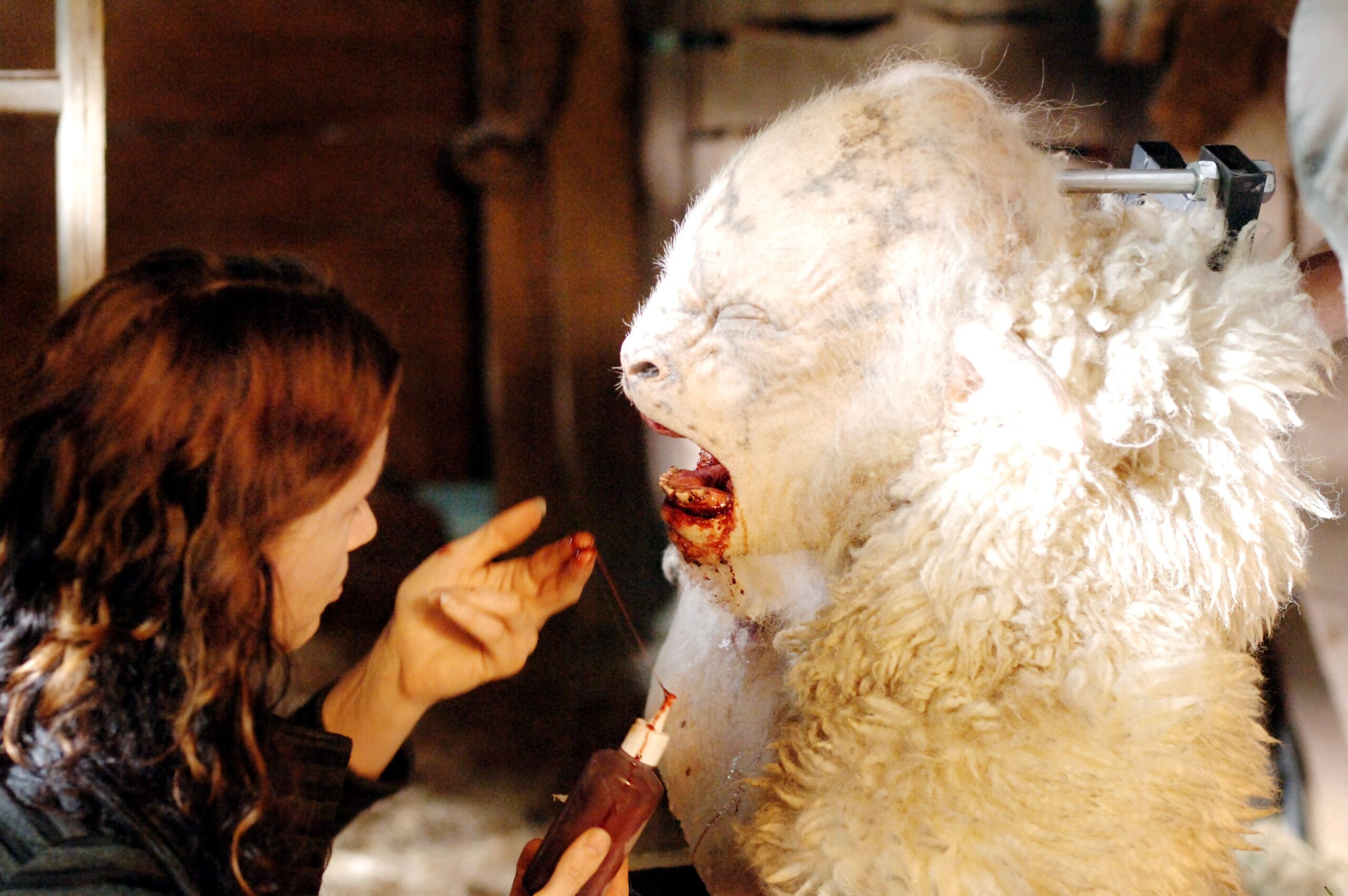 A woman involved in Weta's Workship adds fake blood to the head of a sheep animatronic.