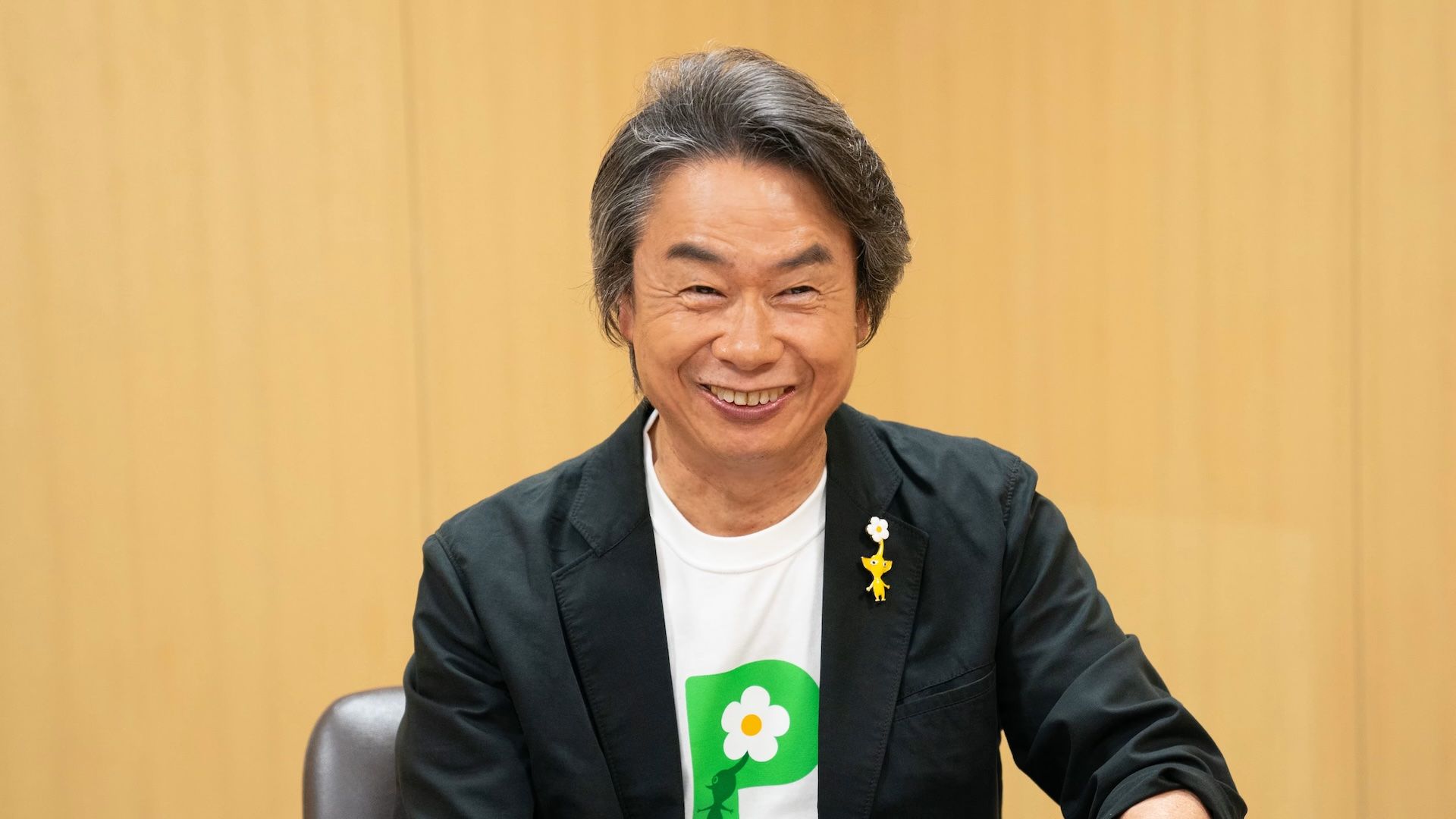 A photograph of Nintendo's Shigeru Miyamoto wearing a Pikmin t-shirt and pin